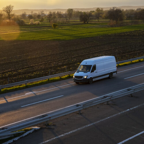 White delivery van on the highway. White modern delivery small shipment cargo courier van moving fast on motorway road to city urban suburb. The world’s best transport of goods.
